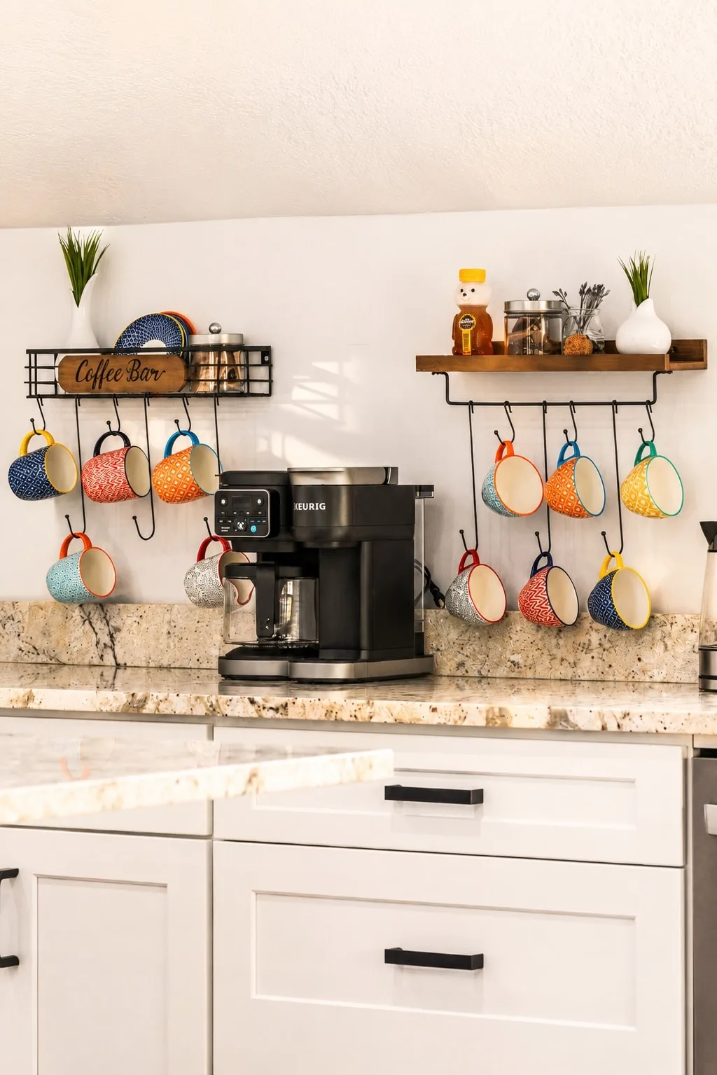 Sky Suite's dedicated coffee bar with a Keurig, hanging colorful mug collection, honey bear, and a wooden Coffee Bar sign — the amenity Vrbo highlights.
