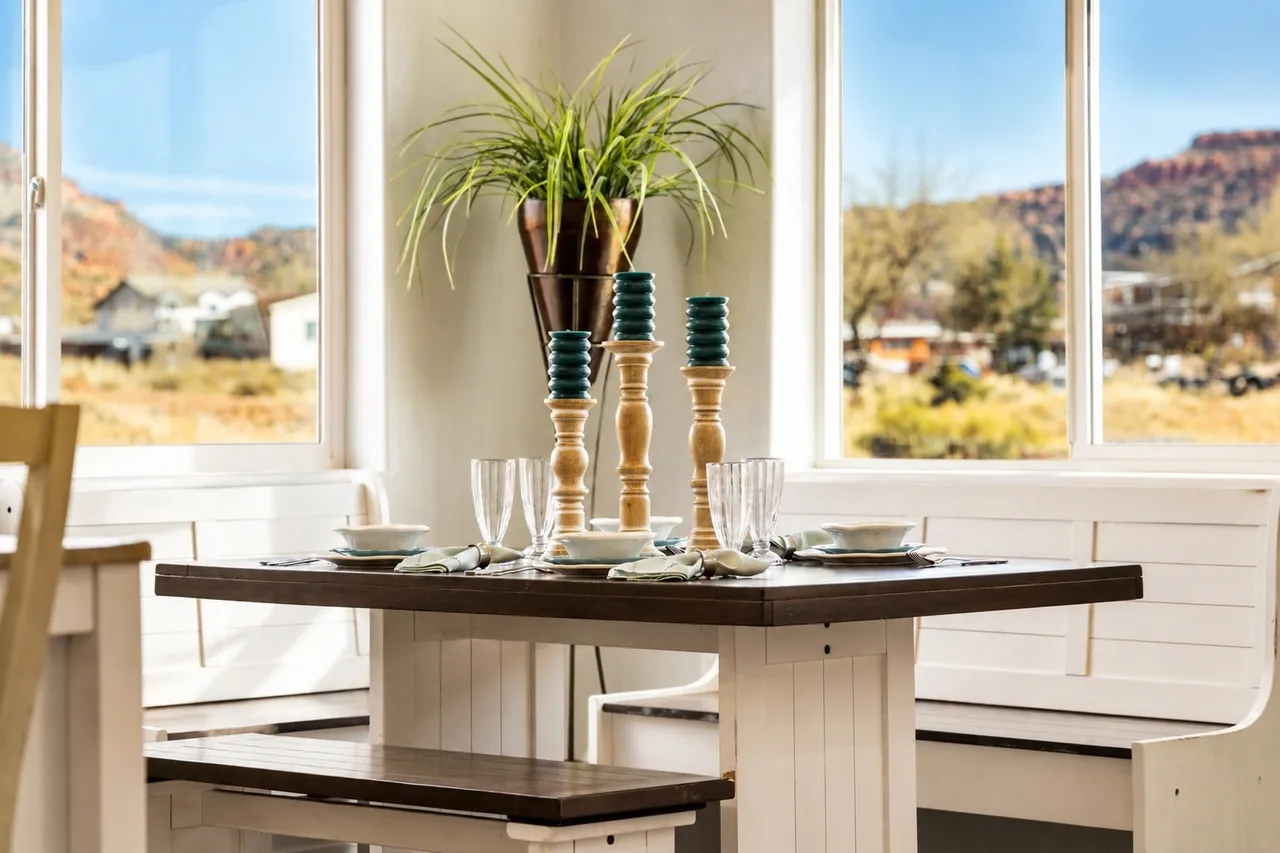 Sunlit booth-style breakfast nook in the Garden Suite with wooden candlesticks, place settings for four, and red-cliff views on both sides.